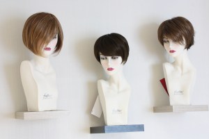 3 têtes de perruques, portant des perruques courtes, exposées sur des étagères