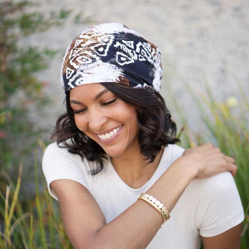 Femme souriante portant un turban avec un imprimé composé de noir, de blanc et de marron avec des triangles blancs