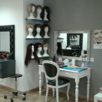 Fauteuil de salon de coiffure noir placé face à un miroir avec des têtes de mannequins portant des perruques ou des turbans