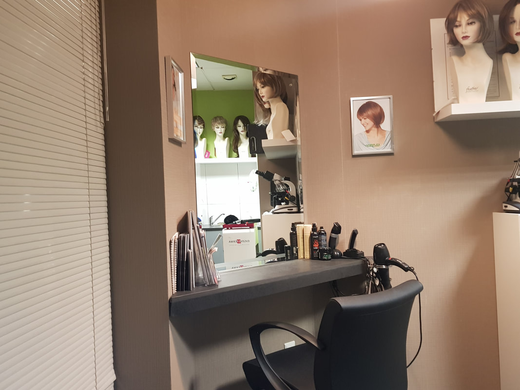 salon de coiffure avec un fauteuil noir face à un miroir