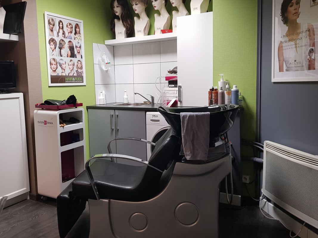 Salon de coiffure, cabine individuelle, avec un fauteuil, un bac à shampoing, un évier et des perruques exposées