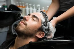 Homme se faisant shampouiner la tête aux bacs à shampoings